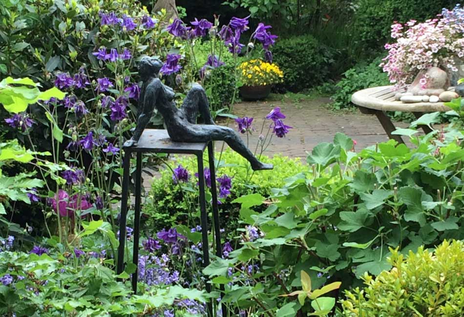 Tuin met akelei en beeld